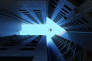 Buildings making arrow sign plane flying in sky Andriy Onufriyenko