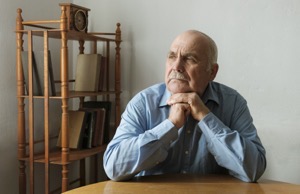 Elderly man seated at a table thinking 2022 12 16 12 35 23 utc