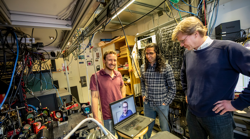 Dolev Bluvstein, Harry Levine (on the laptop), Sepehr Ebadi and Mikhail Lukin, on right, standing next to their neutral atom quantum computer, on left. Their new quantum processor can move atoms while preserving their quantum entanglement, enabling new types of computations where any two qubits can be entangled, even if they are far apart. Credit: Rose Lincoln/Harvard Staff Photographer