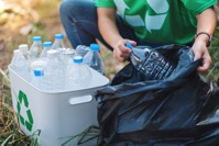 A woman picking up garbage plastic bottles into a JGVJKAF