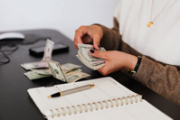 Crop payroll clerk counting money while sitting at table Free Stock Photo