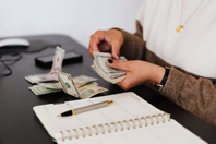 Crop payroll clerk counting money while sitting at table Free Stock Photo