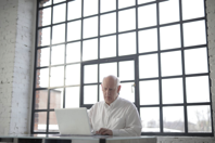 Man in White Shirt Sitting by the Table Using Macbook Free Stock Photo