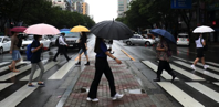 people crossing the street with umbrellas