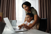 Mother and child workign on latop computer.