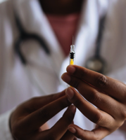 Dose of vaccine in needle held by nurse.