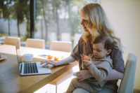 Mom working on laptop with child in her lap.