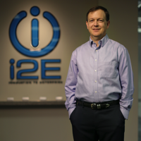 Scott Meacham in front of i2E's logo