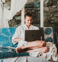 Smiling Woman Using Macbook While Sitting on Sofa Free Stock Photo