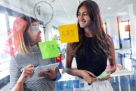 Two business young women working together on wall V5VFEKE