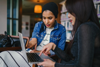 Two Women Looking And Pointing At Macbook Laptop Free Stock Photo