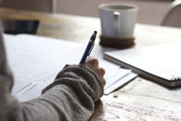 Person holding pencil with papers in front of them.